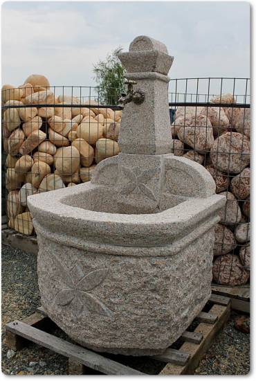 Das ist ein Gartenbrunnen aus Granit mit eingearbeiteten Relief in Form einer Blume.