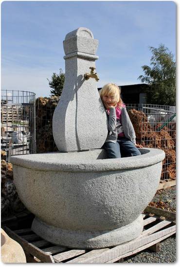 Das ist ein ein großer Gartenbrunnen aus Granit, der halbrund geschwungen ist.