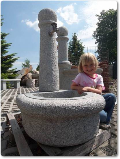 Das ist ein Granitbrunnen mit rundem Erscheinungsbild. In der Brunnensäule befindet sich ein Wasserhahn aus Messing.