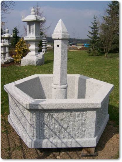 Das ist ein mächtig wirkender Dorfbrunnen mit sechseckiger Form und gestockten Oberflächen aus Granit.